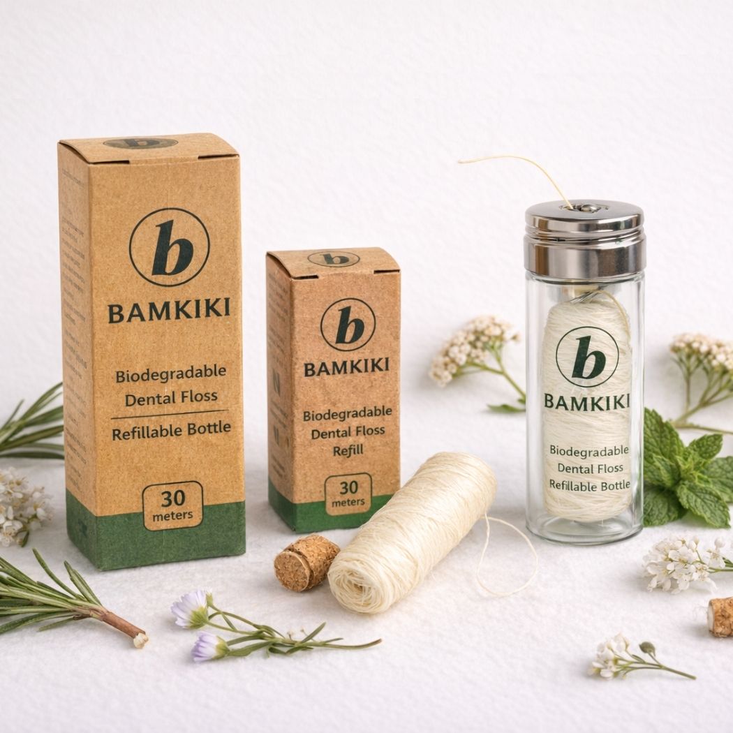 Bamkiki biodegradable dental floss packaging and refill on a white background with greenery.