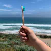 Bamkiki toothbrush review from holding with hands the ocean background with an eco friendly biodegradable sustainable bamboo toothbrush